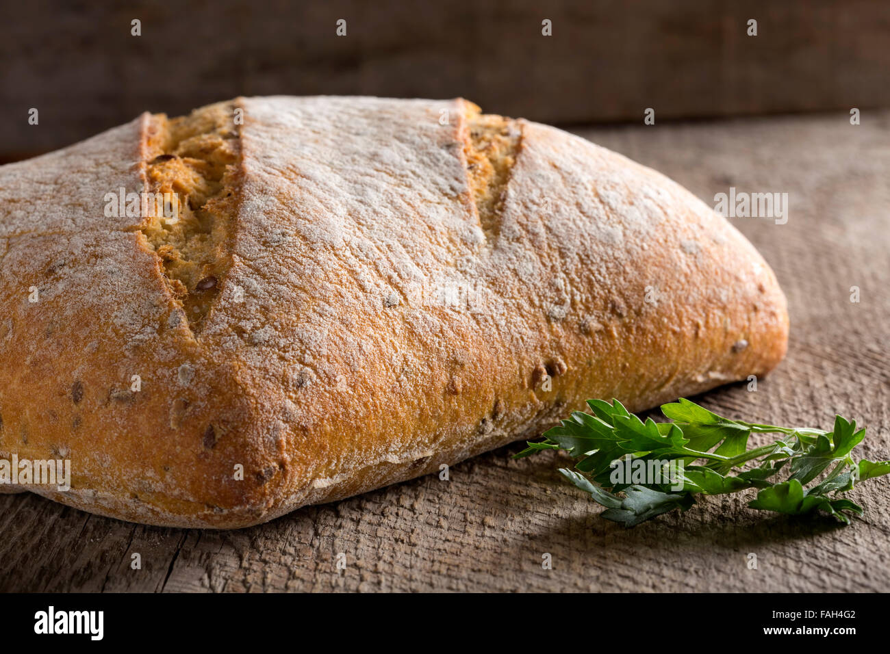 Hausgemachte frisch gebackenes Brotlaib und Petersilie über rustikale Holz Hintergrund Stockfoto