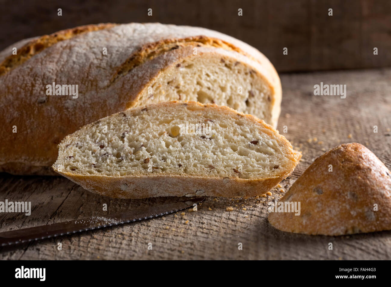 Schnittbrot mit Samen und Messer über alten rustikalen hölzernen Hintergrund Stockfoto