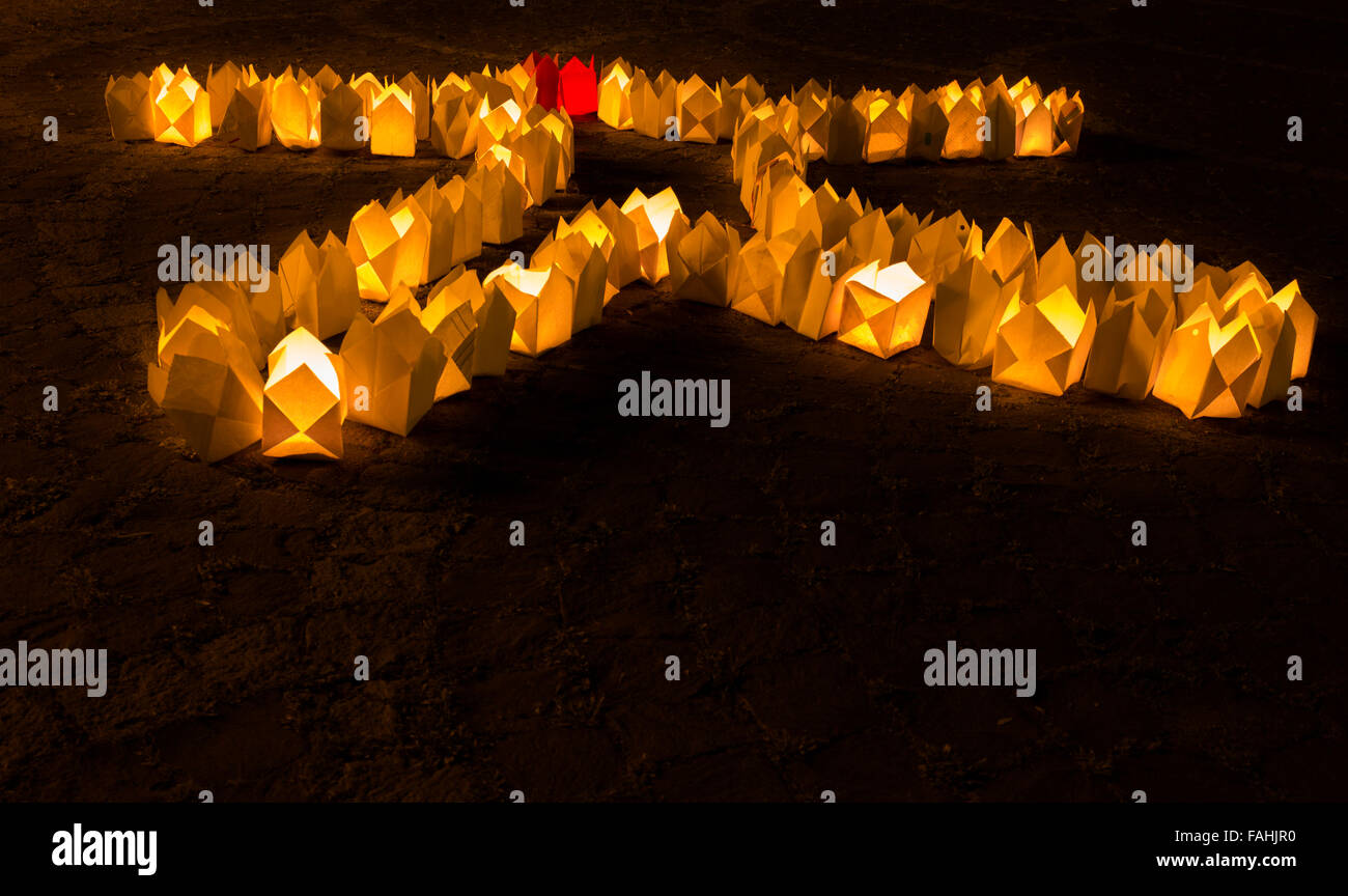 Leuchtend gelbe und rote Kerzelichter aus Papier in der Dunkelheit, in Form eines menschlichen Wesens gemacht Stockfoto