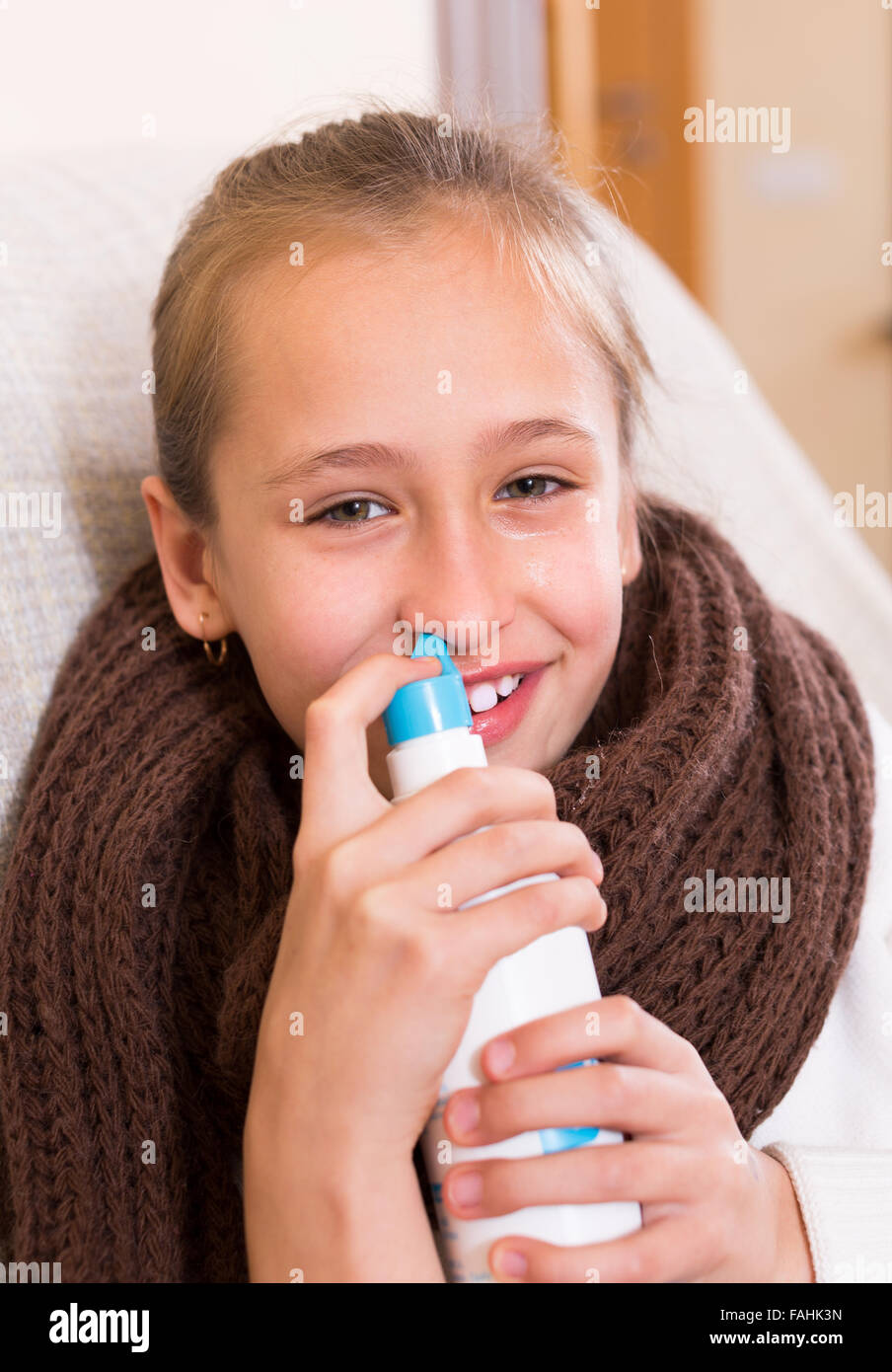 Krank Schulmädchen mit nasalen Sprühgerät für Rhinitis auf Couch sitzen Stockfoto