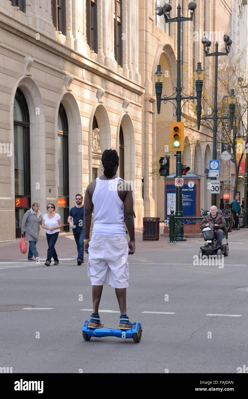 Junger Mann reitet auf einem motorisierten Hoverboard auf einer Stadtstraße Zentrum in Calgary, Alberta, Kanada. Stockfoto