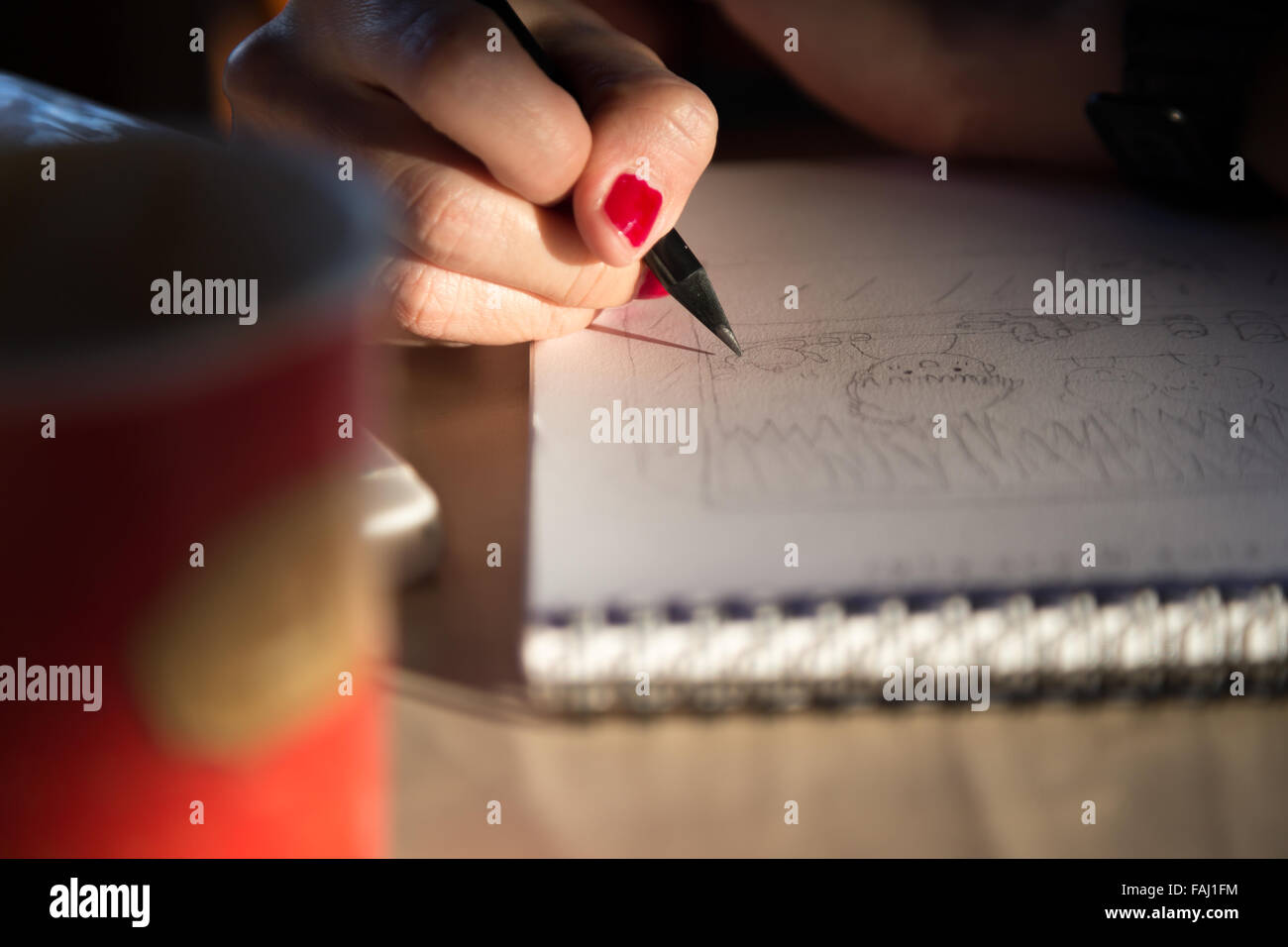 Hand mit roten Nagel halten Bleistift skizzieren Papierarbeiten mit Sonnenlicht Stockfoto