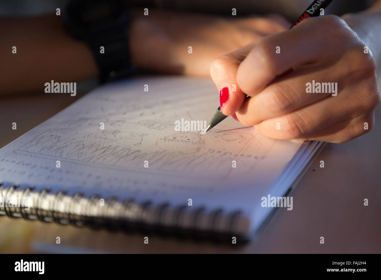 Hand mit roten Nagel halten Bleistift skizzieren Papierarbeiten mit Sonnenlicht Stockfoto