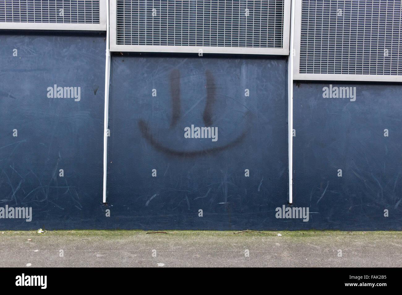 Smiley-Gesicht gesprüht auf blaue Wand Stockfoto