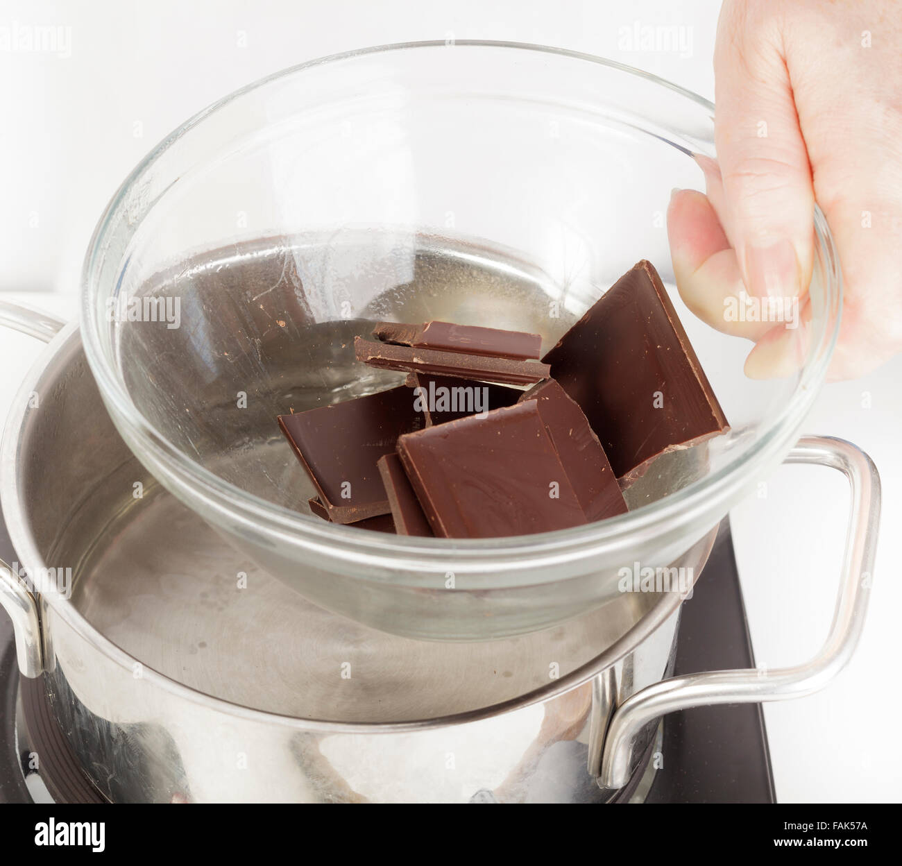 Putting Schüssel mit Schokolade über Topf mit Wasser zum Schmelzen als Bain Marie Stockfoto