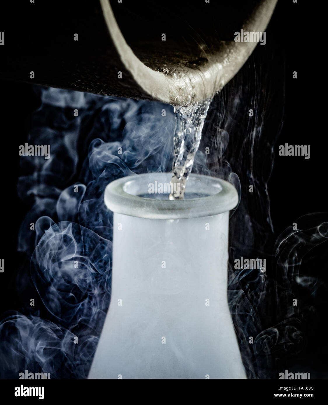 flüssiger Stickstoff wird aus einem Becher in eine Flasche gegossen Stockfoto