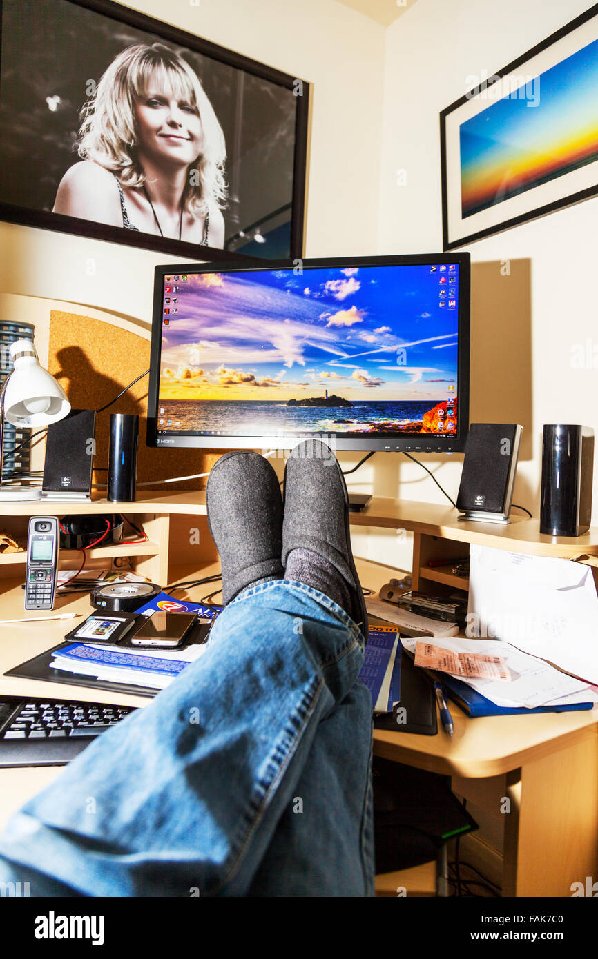 Füße am Schreibtisch Büroangestellter vor Computer Bildschirm Beine entspannen gekreuzt UK England Stockfoto