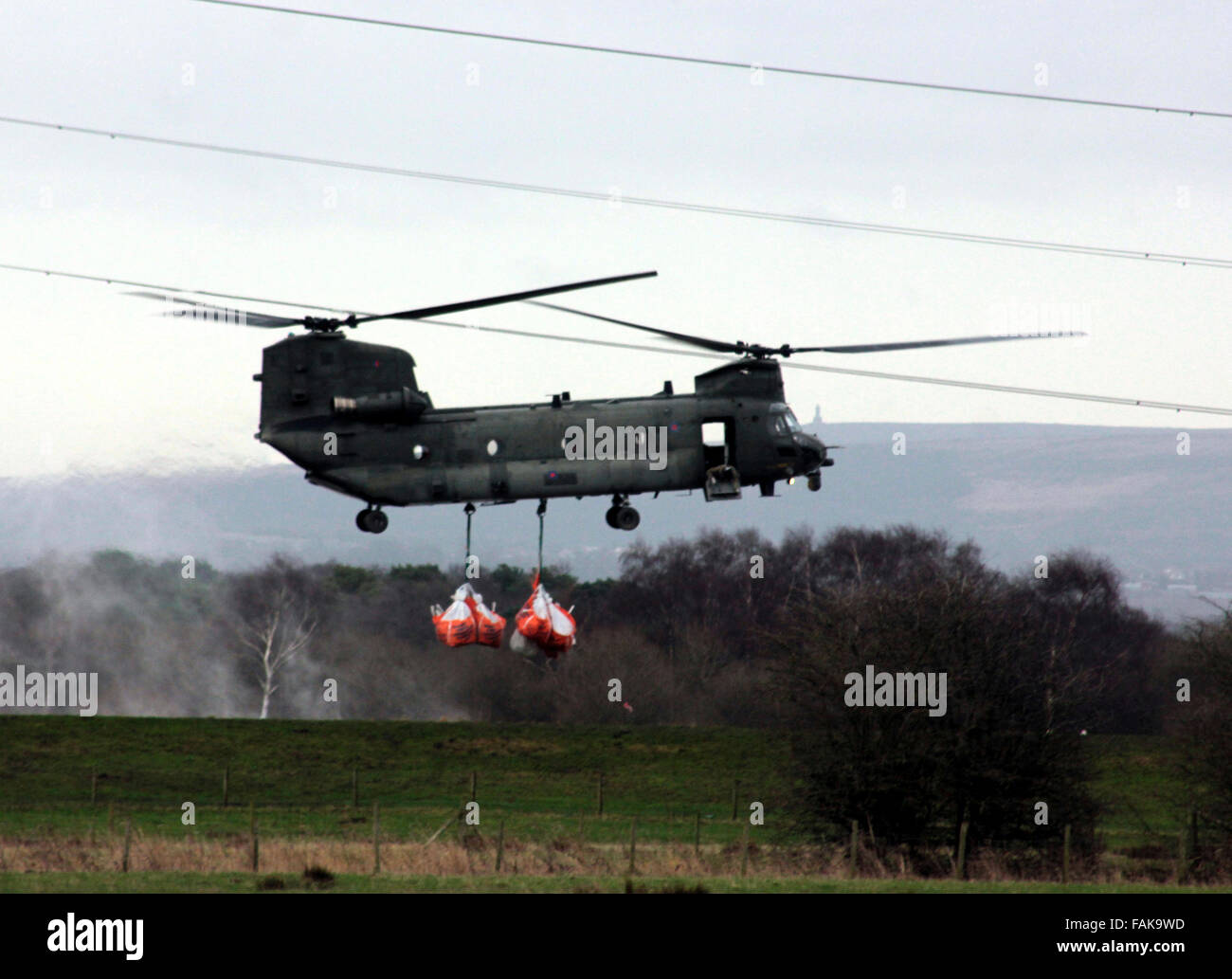 Ein RAF-Chinook-Hubschrauber transportiert acht 1 Tonne Säcke mit Sand, den Lauf des Flusses Douglas in der Nähe von Croston in West Lancashire Stockfoto