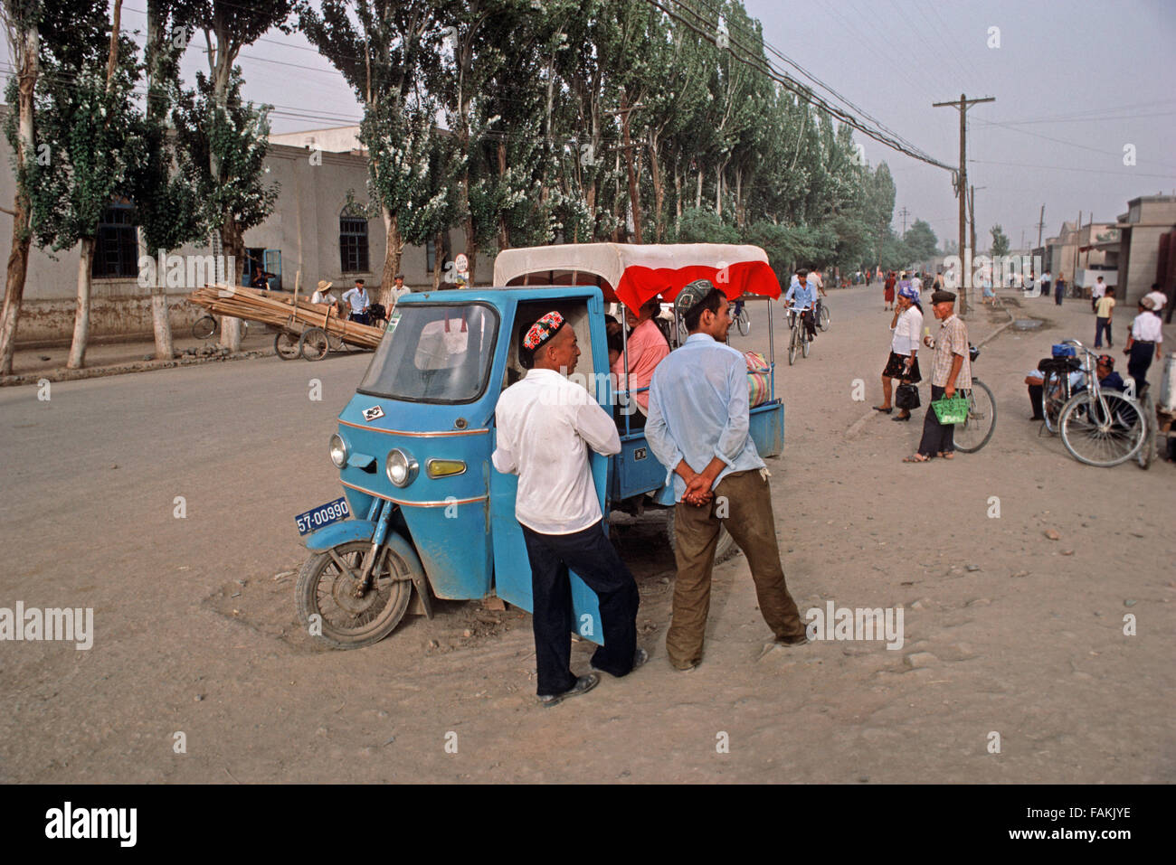 Uyghur Männer neben Motorrad Taxi in Turpan, Provinz Xinjiang, China Stockfoto