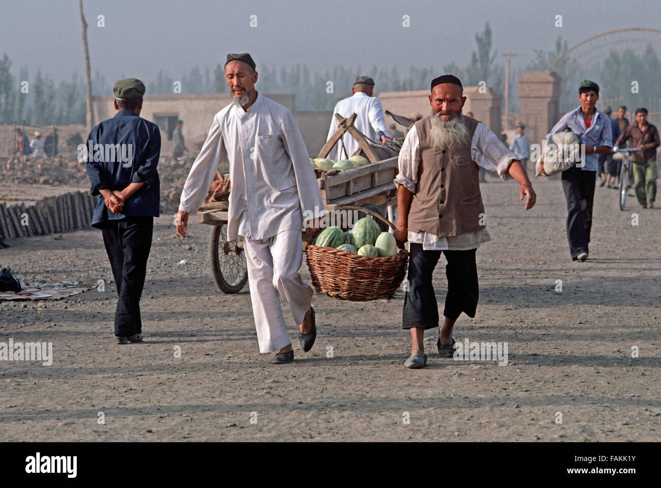 Uyghur-Männer, die die Melonen in Turpan Markt, Provinz Xinjiang, China Stockfoto