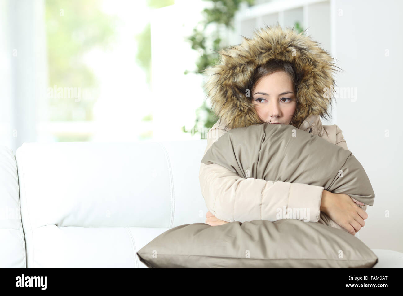 Böse Frau warm gekleidet in eine kalte Heimat sitzen auf einer couch Stockfoto