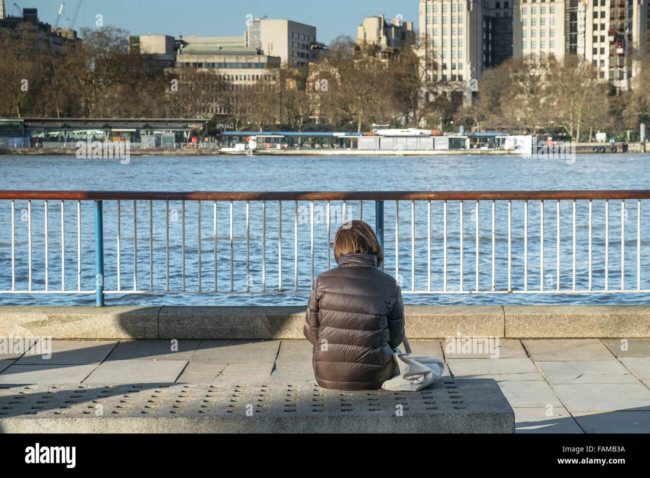 Eine Frau sitzt auf ihr eigenes auf der South Bank in London. Stockfoto