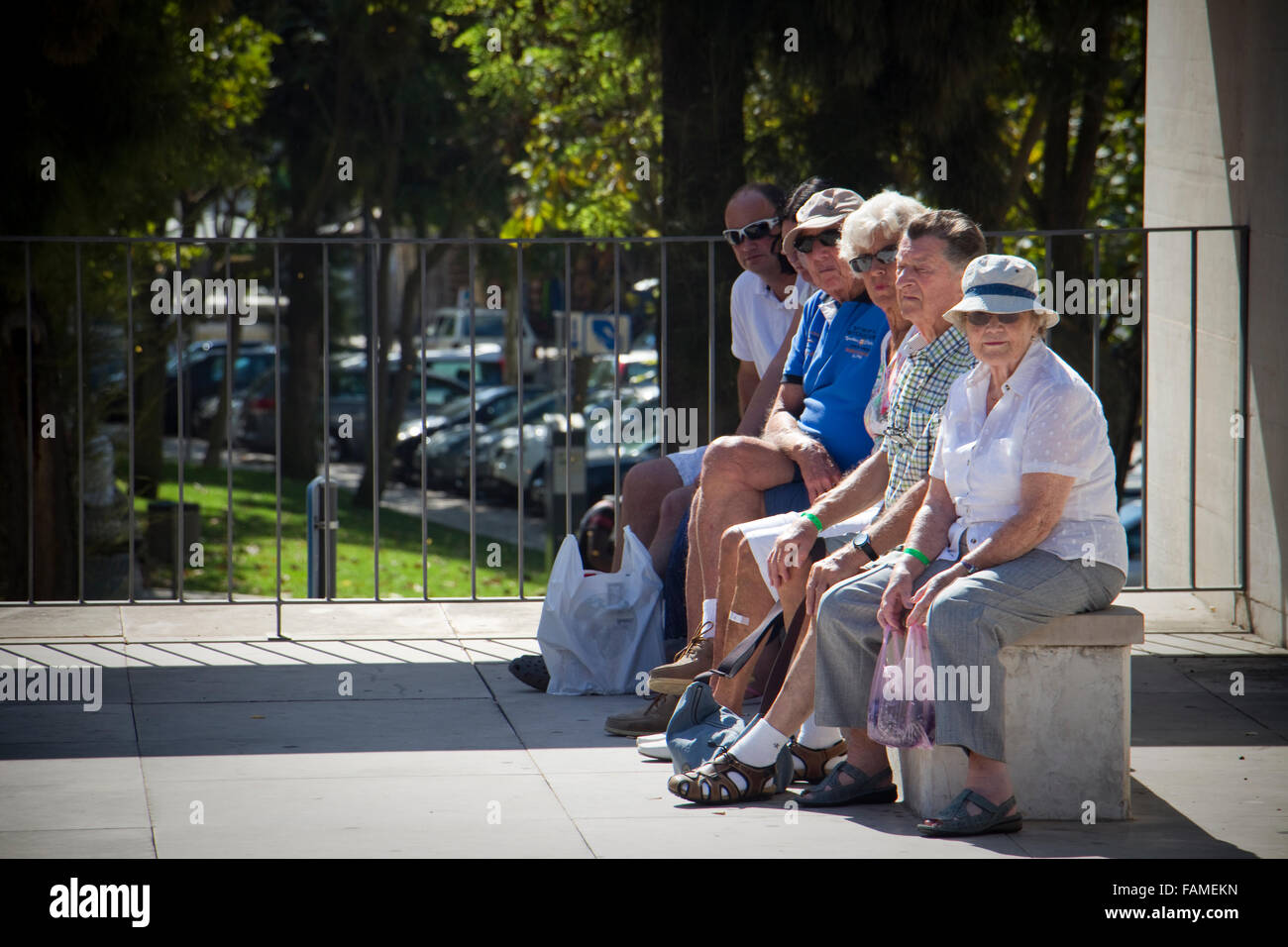 Menschen saßen auf einer Bank einen Bus warten. Albufeira, Algarve, Portugal Stockfoto