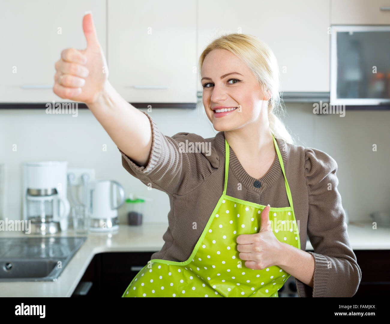 Glücklich Blondine in Küche und zeigt Daumen hoch Stockfotografie - Alamy