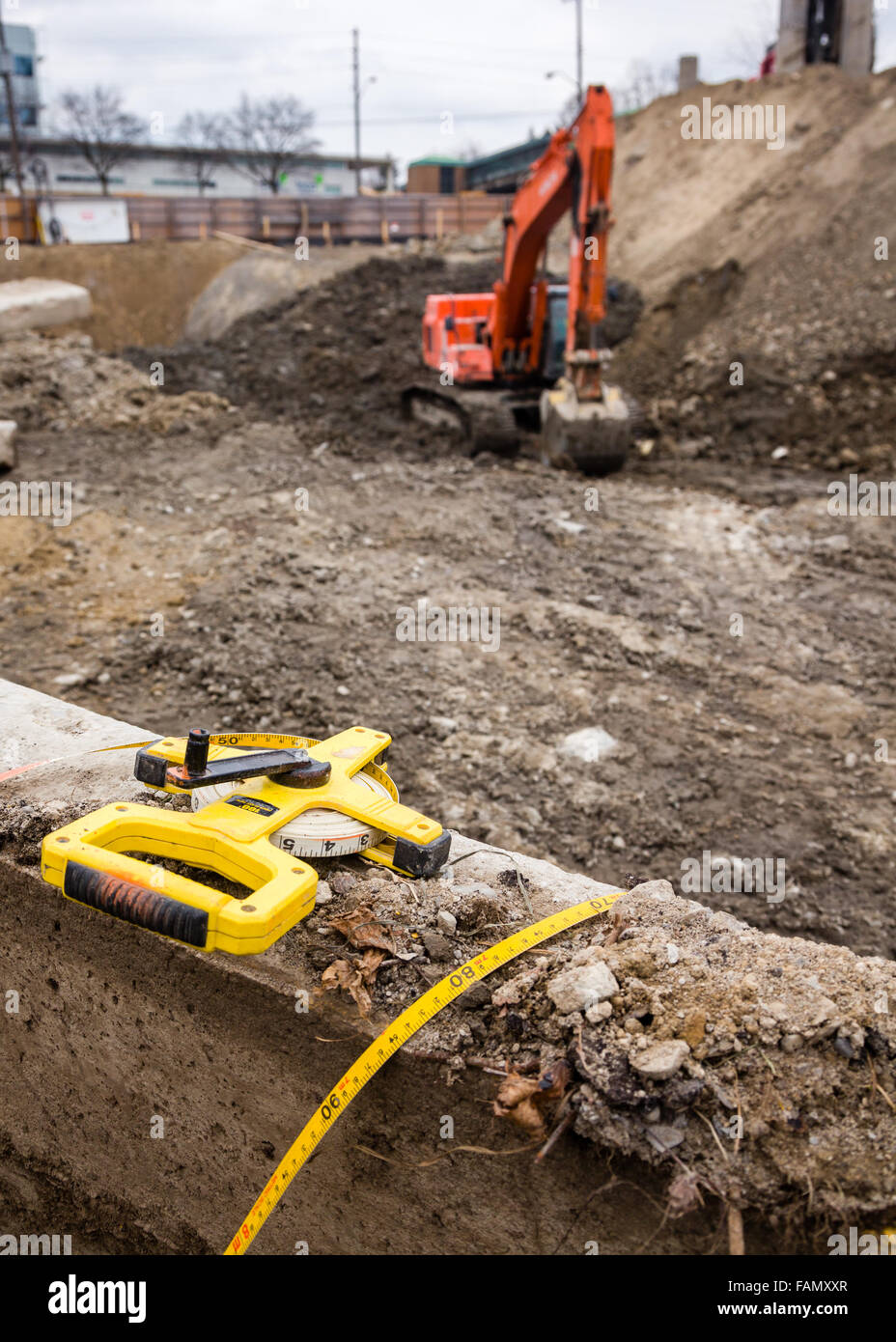 Bau Website Ausgrabung. Industrielle Maßband im Vordergrund mit einem Bagger im Hintergrund. Stockfoto