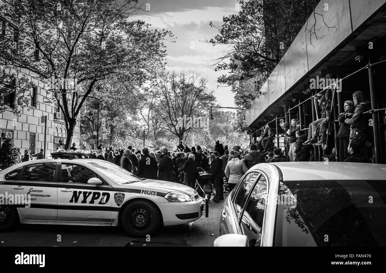 Eine Menge von Zuschauern zu sehen, die 2015 Macy's Thanksgiving Day Parade und ein NYPD-Streifenwagen in schwarz / weiß Stockfoto