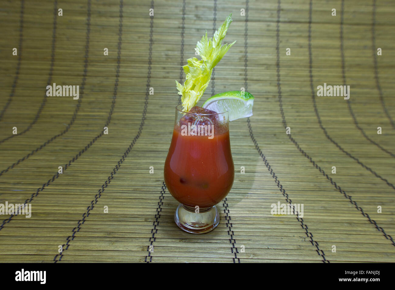 Bloody Mary oder blutige Caesar cocktail oder Glas Tomatensaft mit Limettenschnitz und Sellerie Stengel auf Bambusmatte. Stockfoto