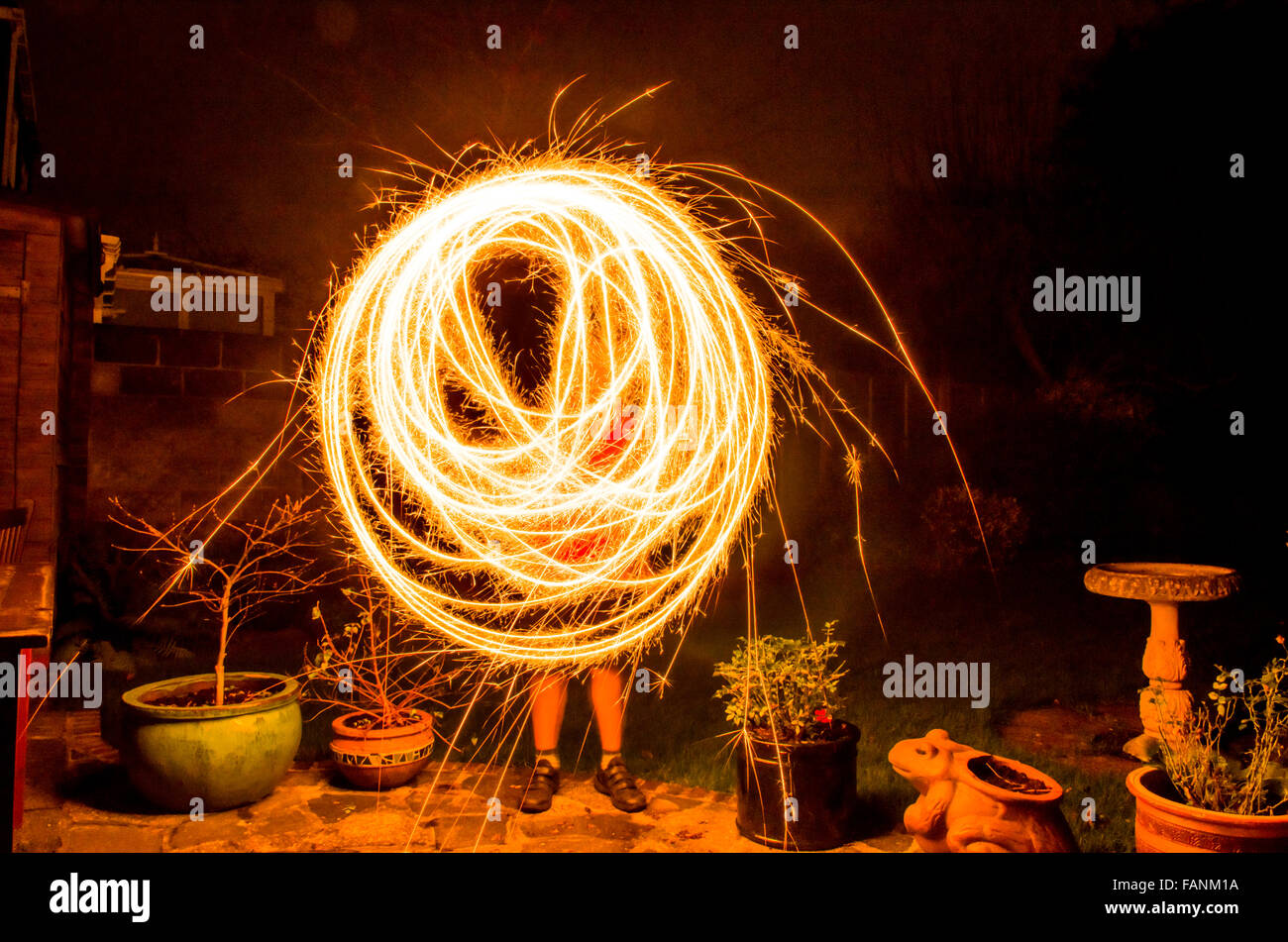 Neun-Jahr-alte junge holding Feuerwerk Wunderkerze und drehte es Runde im Garten in der Nacht. Stockfoto