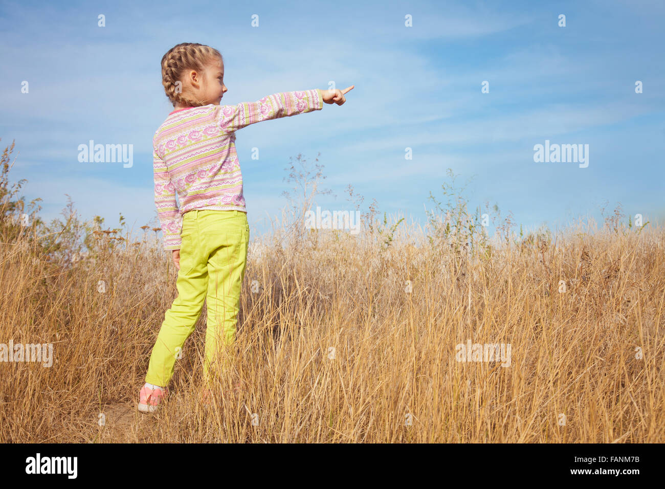 Kleine Mädchen in helle Kleidung zeigt einen Finger in den Himmel Stockfoto