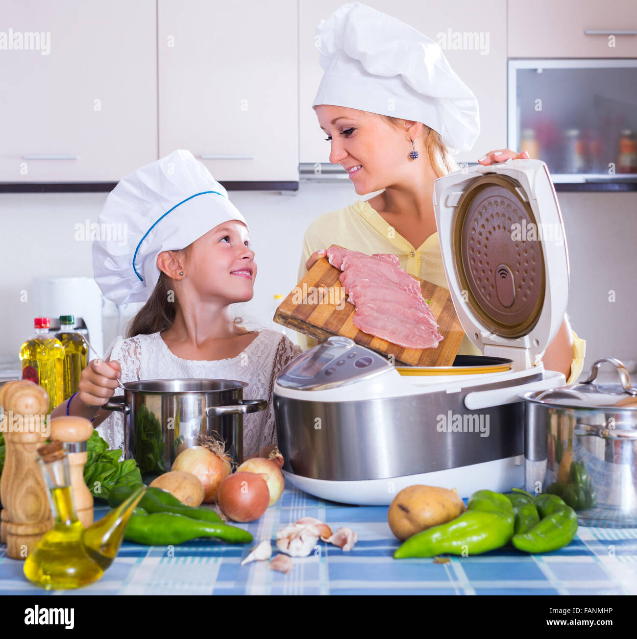 Mutter und glückliches Kind, die Zubereitung von Fleisch im slow cooker Stockfoto