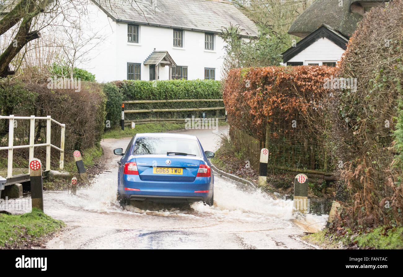 Auto, das durch Wasser in einem überfluteten ford auf einer Landstraße nach starkem Regen in New Forest, Hampshire, England, Großbritannien fährt Stockfoto