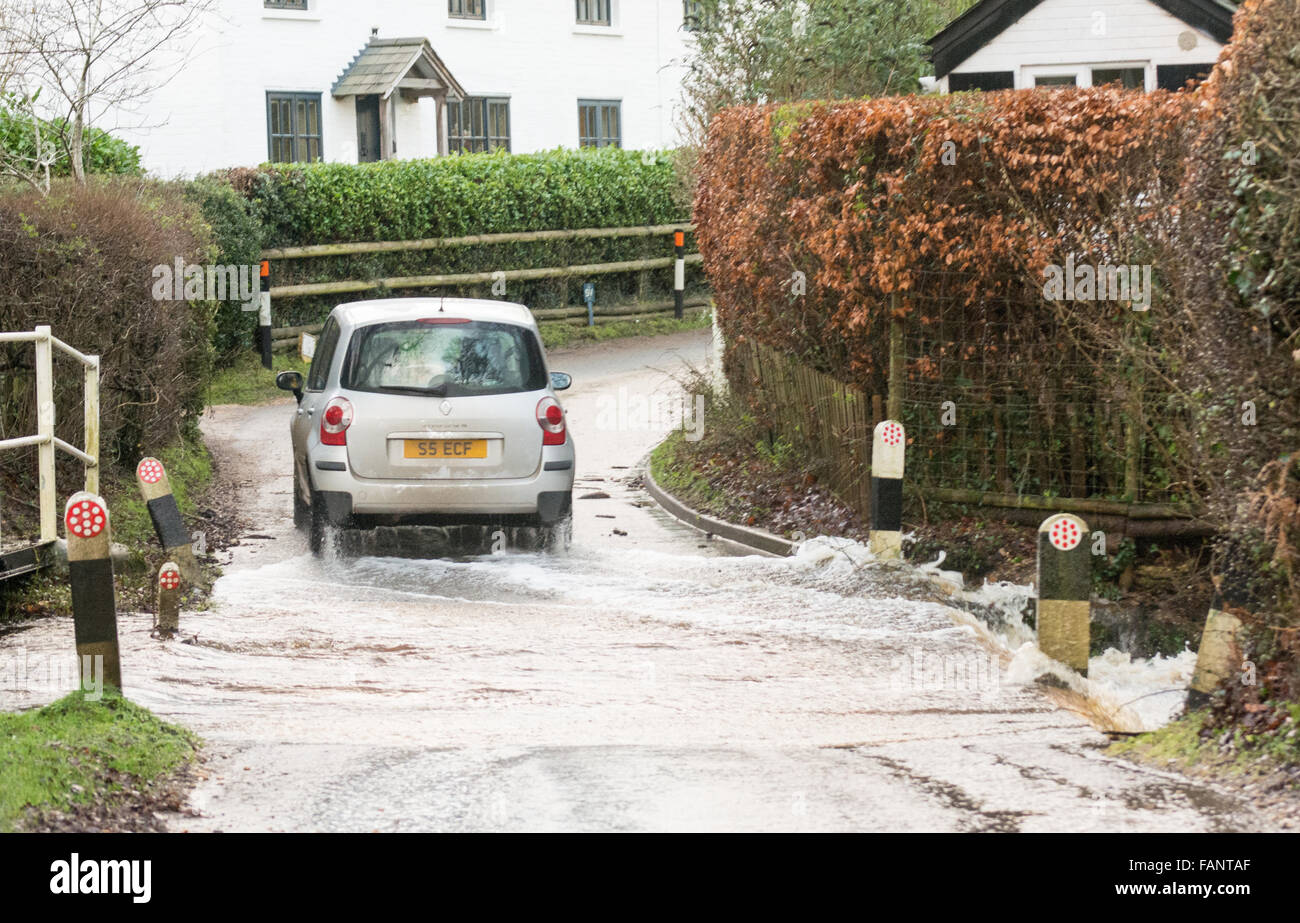 Auto, das durch Wasser in einem überfluteten ford auf einer Landstraße nach starkem Regen in New Forest, Hampshire, England, Großbritannien fährt Stockfoto