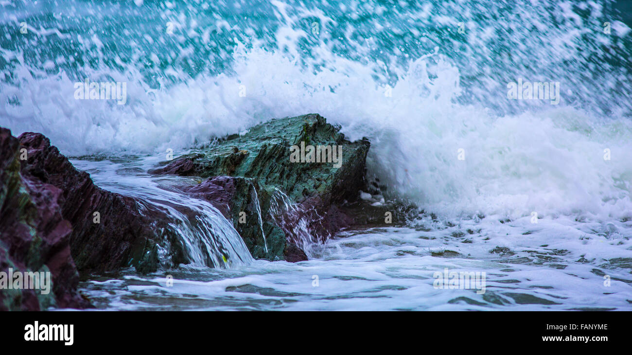 Wellen brechen über Felsen am Polzeath, Cornwall Stockfoto