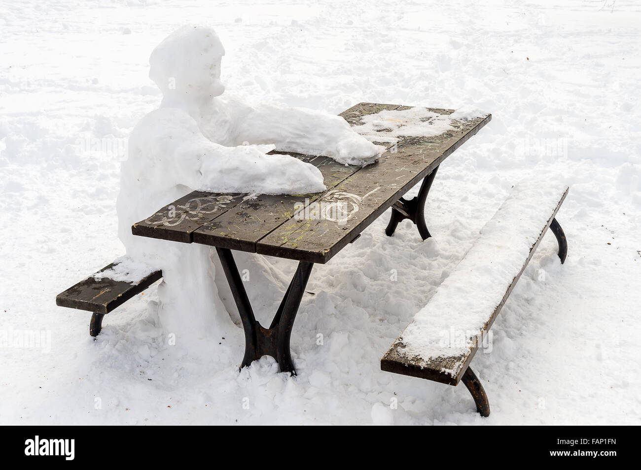 Einsame Schneemann im Picnic Tisch sitzen im Winter Stockfoto