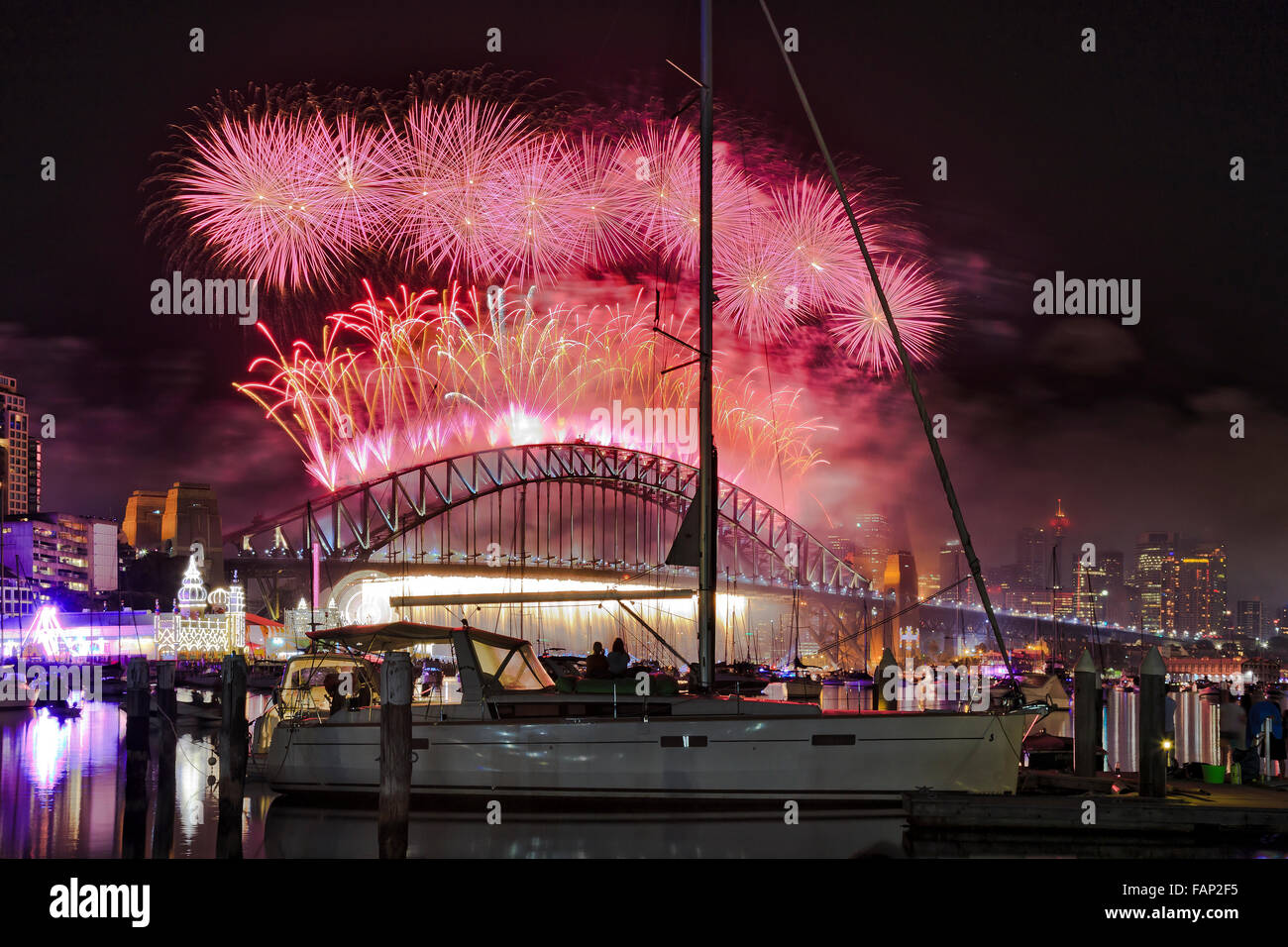 Geschmackvoll farbenfrohen Mitternacht Silvester Feuerwerk über Sydney Harbour Bridge aus Lavendel Bucht mit roten Kugeln und firefall Stockfoto