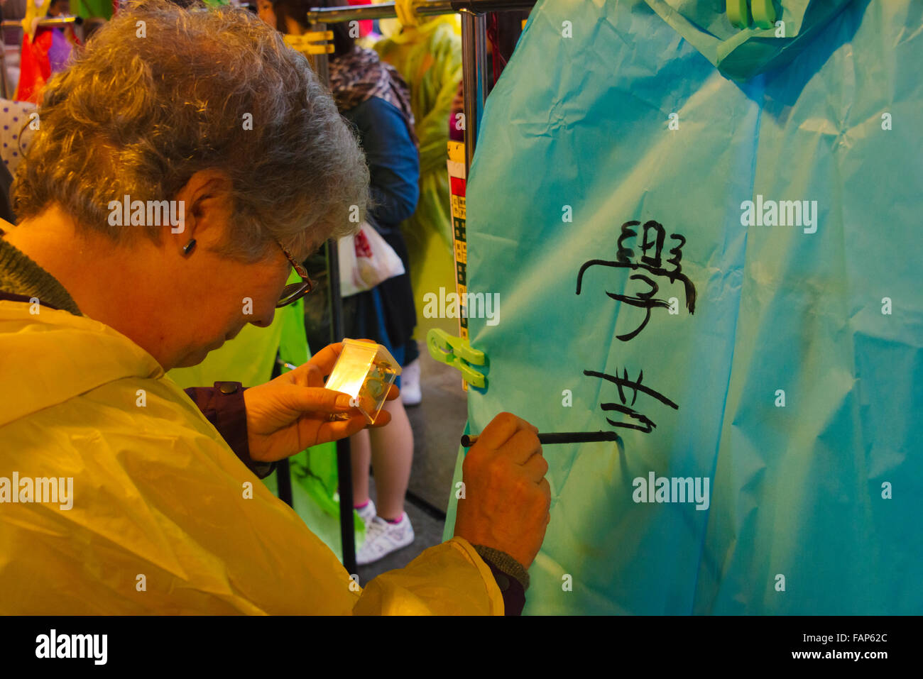 Westliche Touristen schreiben guten Wünsche auf Chinesisch auf Sky Laterne mit chinesischen Pinsel während chinesische Laternenfest, Shifen, Taiwan Stockfoto