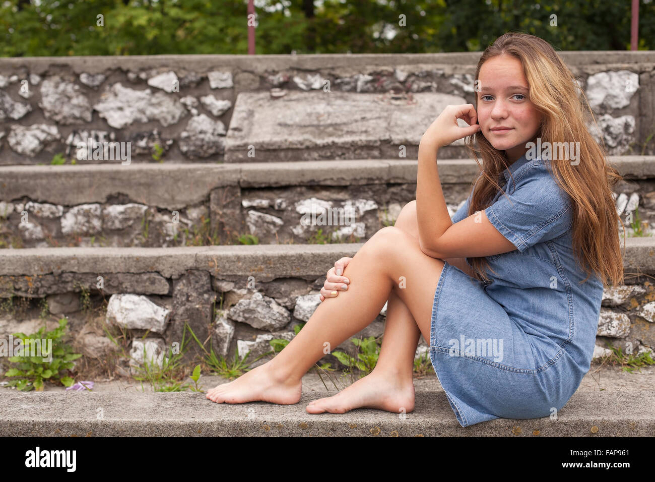 Ein junges Mädchen sitzt auf Steintreppen im Freien. Stockfoto