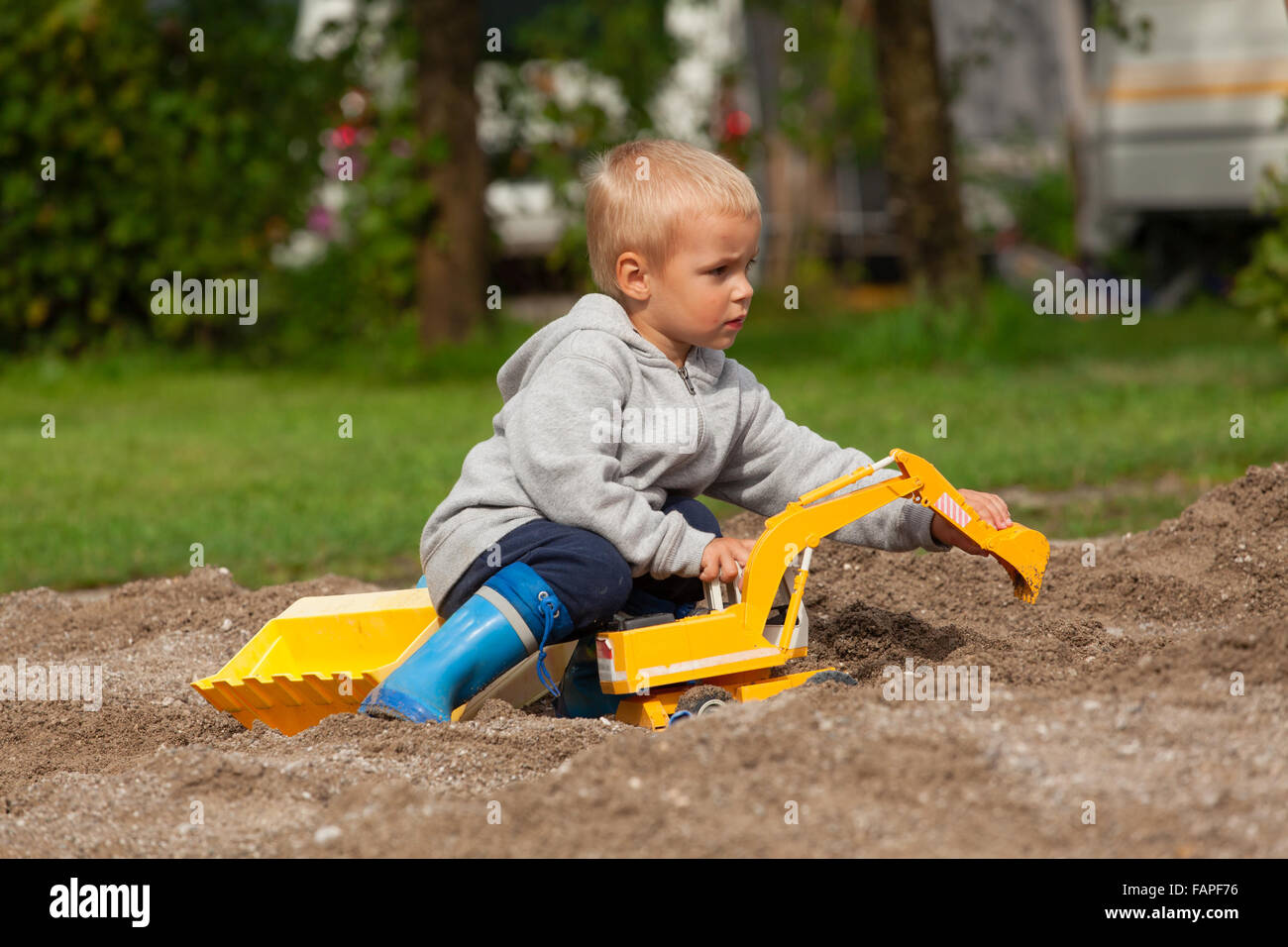 Kleiner Junge mit Kinder Bagger im Sandkasten spielen Stockfotografie -  Alamy