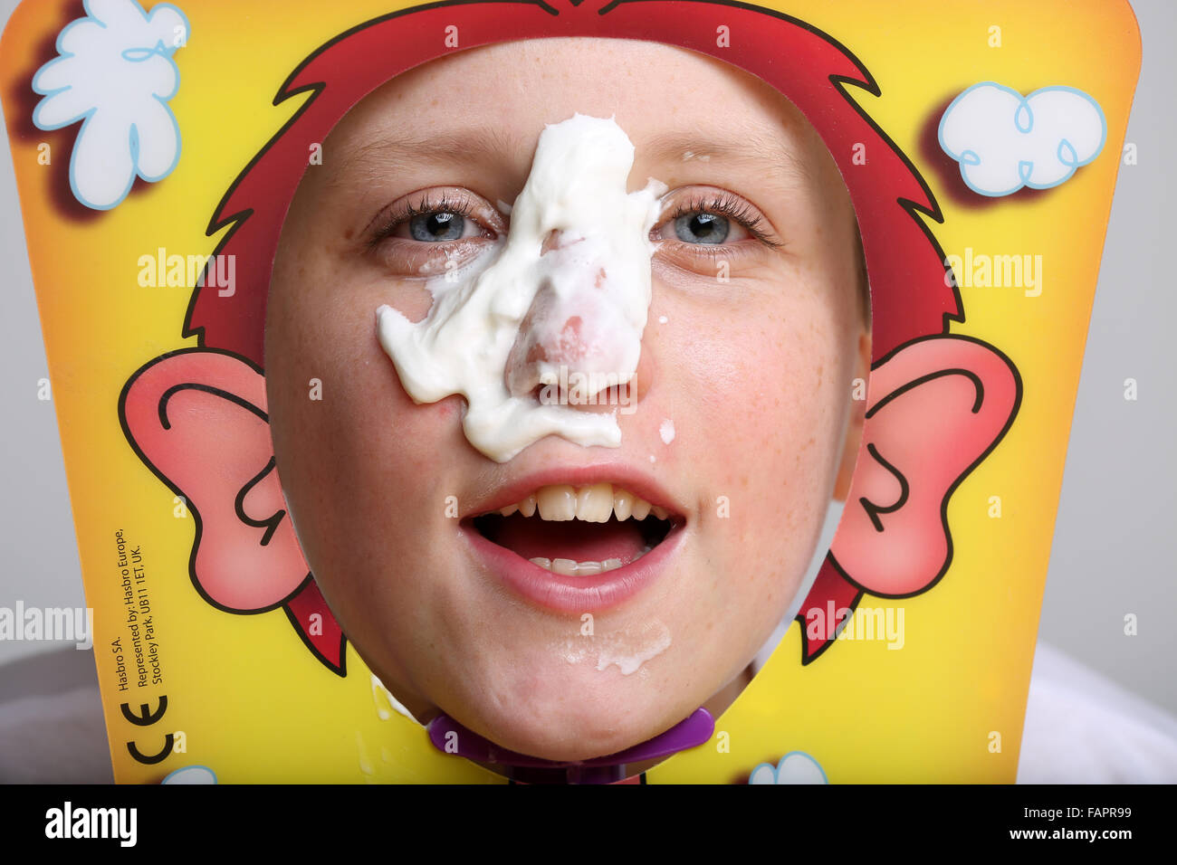 Ein Junge spielt das Brettspiel Pie Gesicht von Hasbro in Creme bedeckt Stockfoto