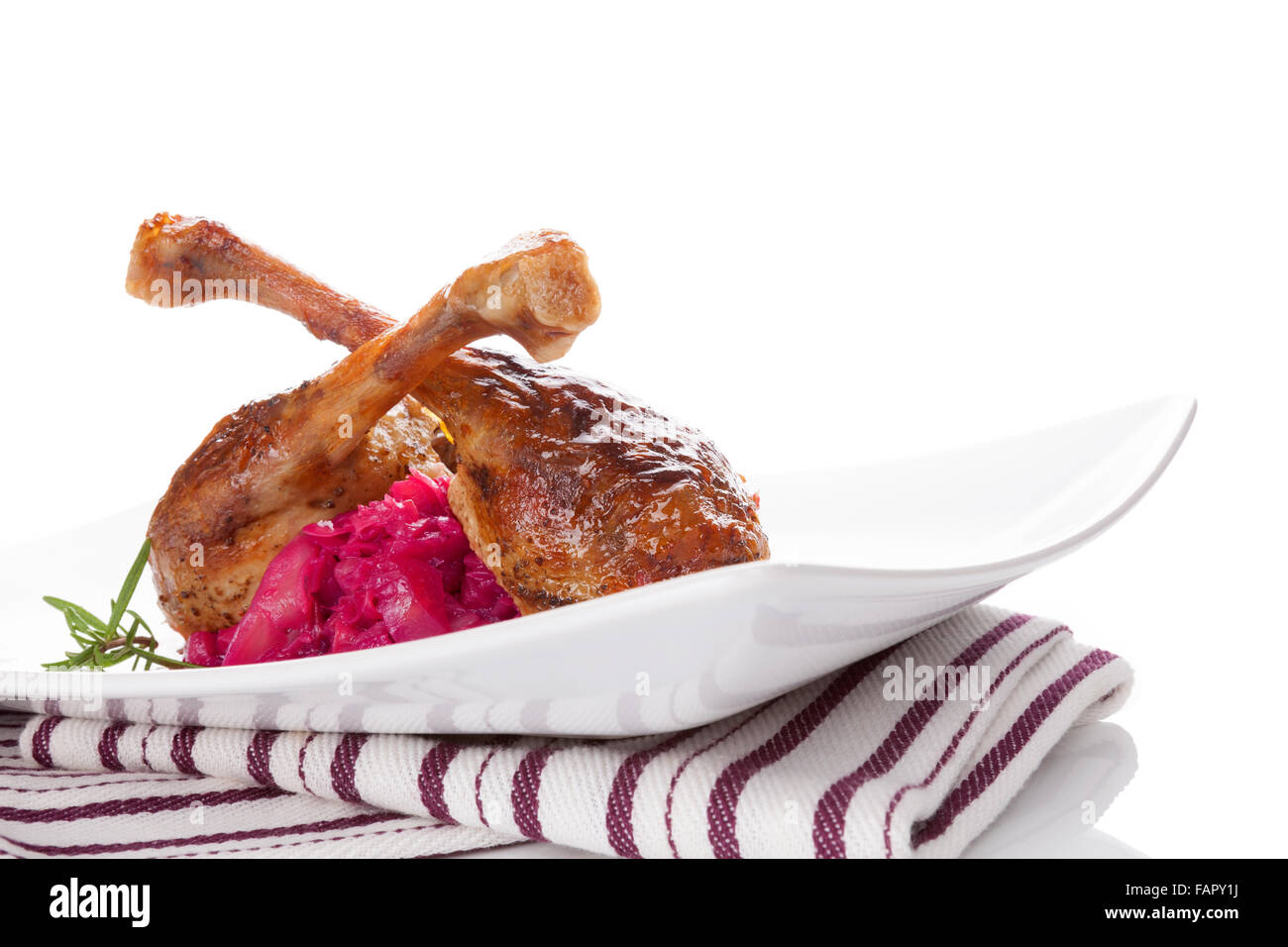 Lecker gebratene Ente mit Rotkohl, traditionelle festliche Essen. Gegrillte Hühnerkeulen mit Rosmarin und Rotkraut. Stockfoto