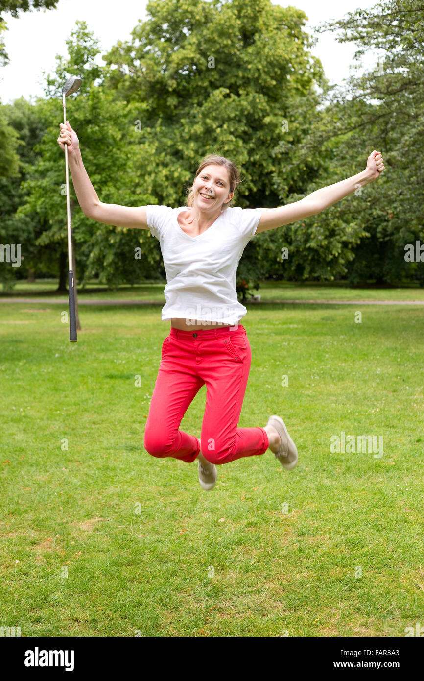 junge Frau mit Freude springen, nachdem ein Hole in one Stockfoto