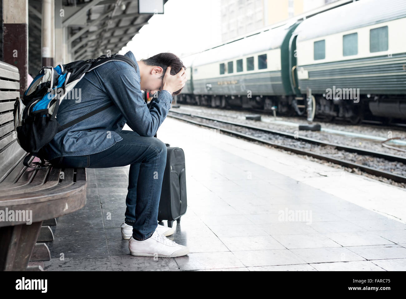 Asiatische deprimiert Reisenden nach Fehlern einen Zug am Bahnhof warten Stockfoto