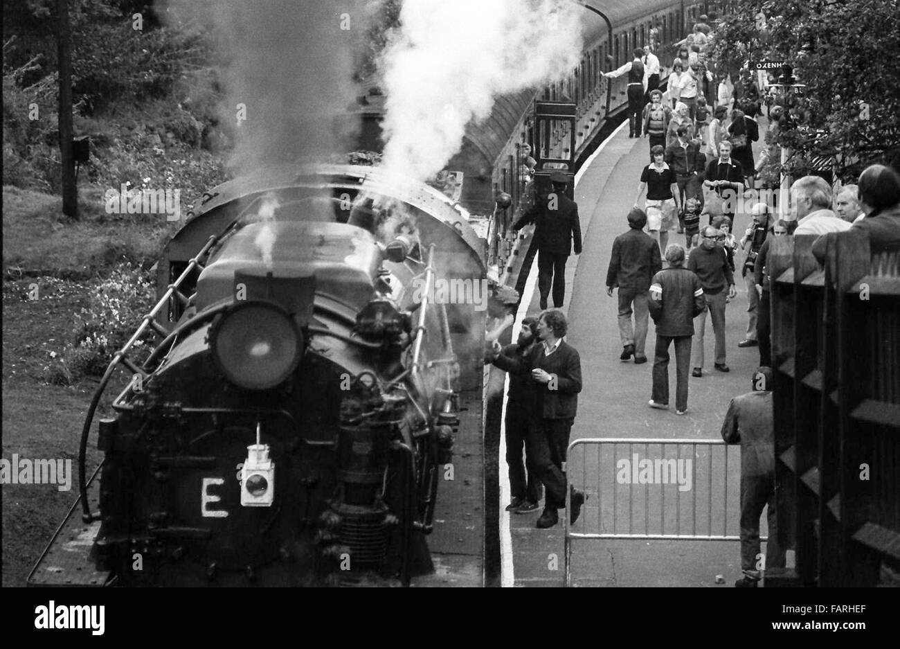 Bahnhof Haworth, West Yorkshire circa 1982 schwarz-weiß Archiv Bild. Heimat der Keighley und Wert Valley Railway, ist die KWVR mit freiwilligen besetzt. Mitarbeiter im Gespräch mit Fahrer und Feuerwehrmann und Passagiere beim Bahnhof Plattform einsteigen. Stockfoto