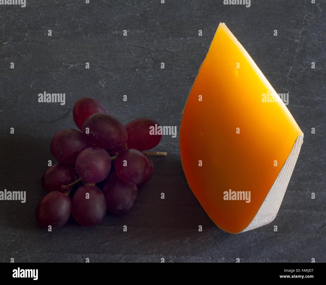 Gelben Stück Käse abstrakte Stilleben mit Trauben closeup Stockfoto