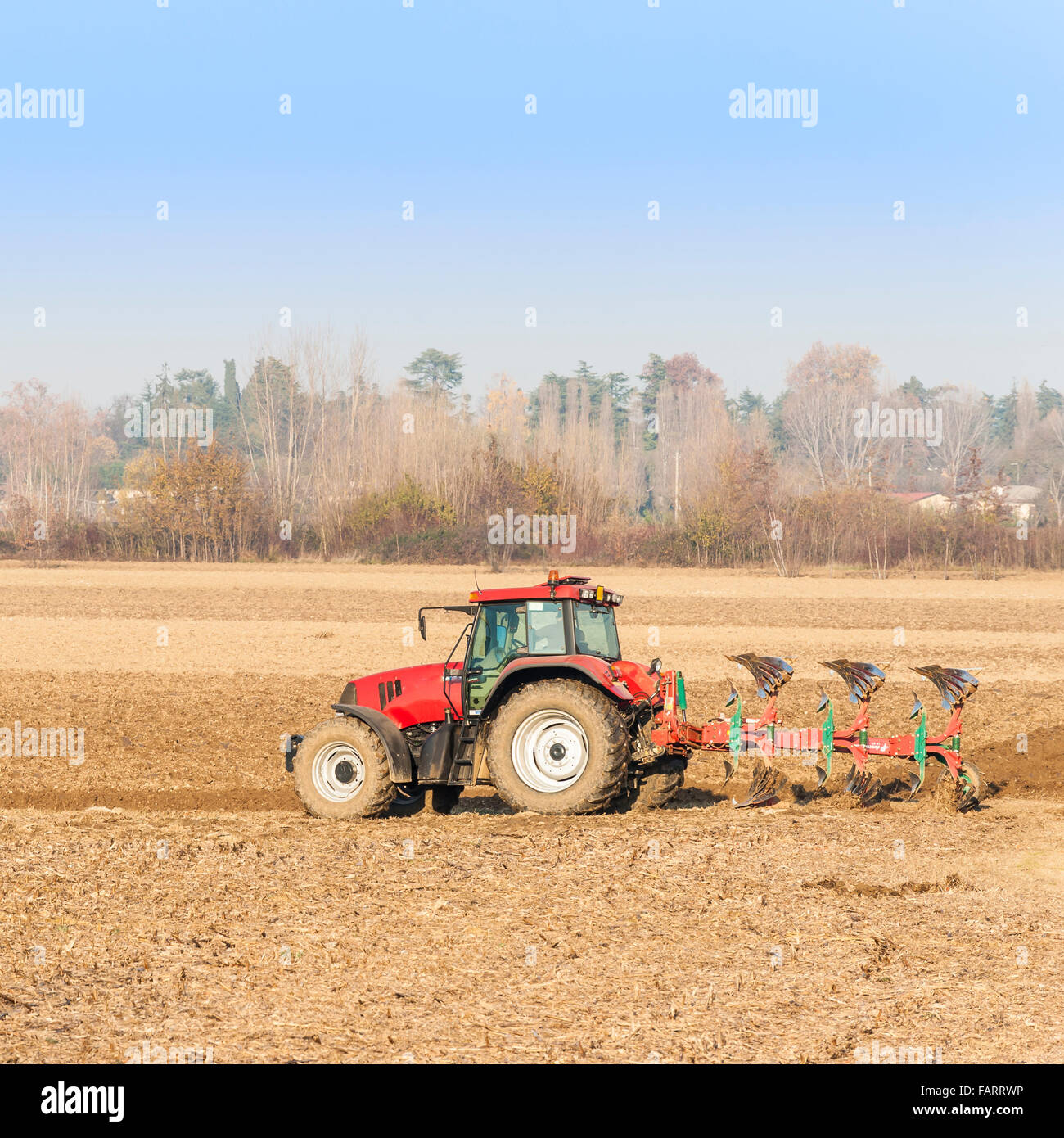 Landwirtschaftliche Arbeit, roter Traktor ein Feld pflügen Stockfoto