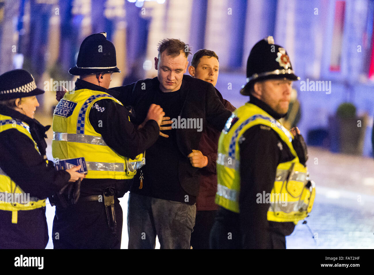 Im Bild: Polizei unterstützen einen Mann braucht Hilfe und auf dem Boden liegend. Re: Silvester in Cardiff, Südwales, UK. EA Stockfoto