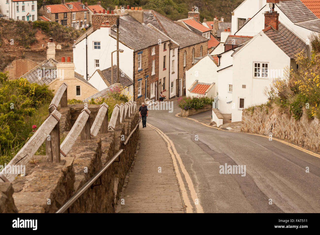 Mann zu Fuß der steilen Ufer an der malerischen Fischerdorf Dorf Staithes, North Yorkshire, England Stockfoto