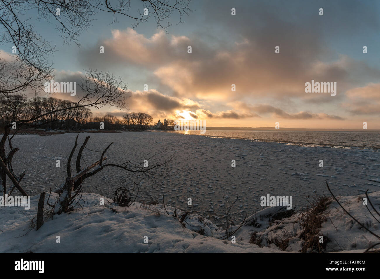 der kalte Rückgang am Ufer des Sees kontrastiert mit warmen Farben des Himmels und der Sonne Stockfoto
