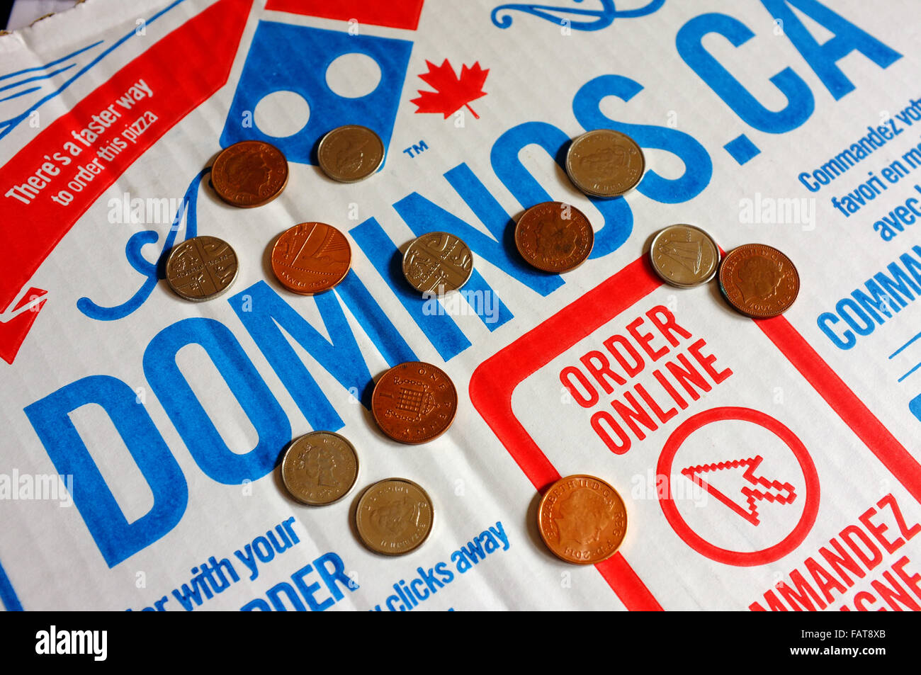Dominos Pizzakarton mit einer Bestellung Online-Anzeige und lose Münzen. Stockfoto
