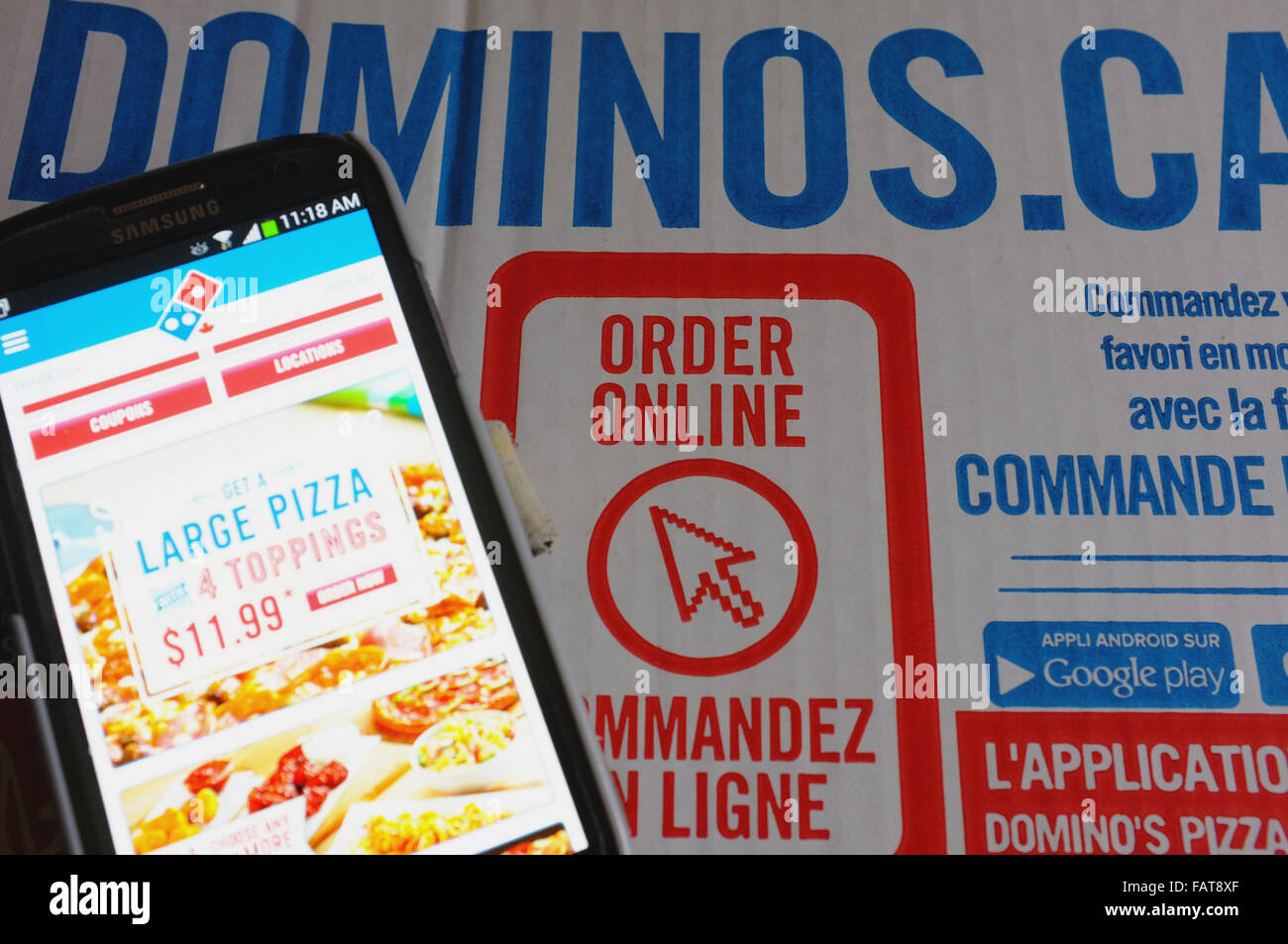 Ein Telefon von einer Dominos Pizza-Schachtel mit einer Bestellung Online-Anzeige auf. Stockfoto