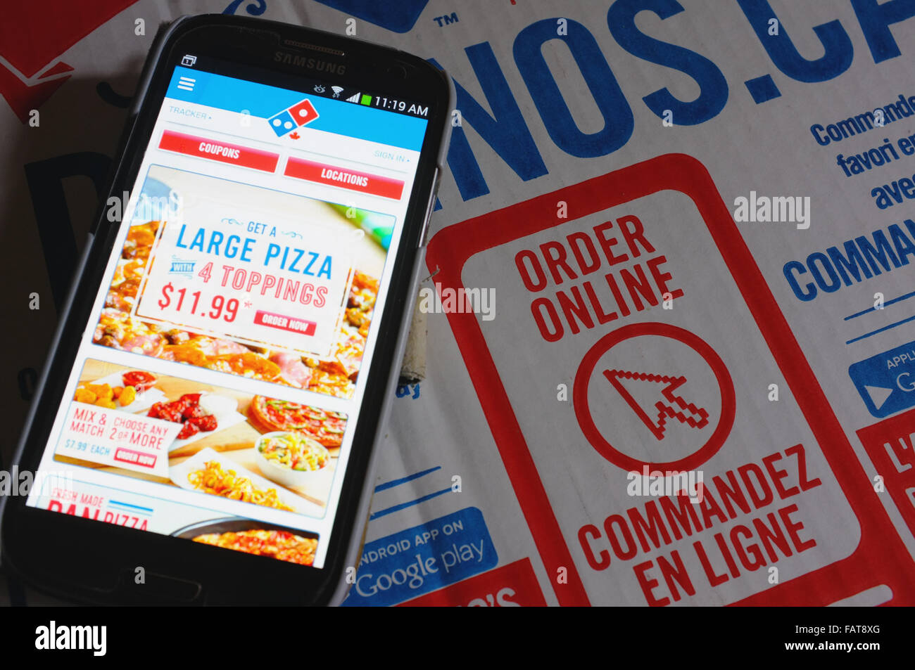 Ein Telefon von einer Dominos Pizza-Schachtel mit einer Bestellung Online-Anzeige auf. Stockfoto