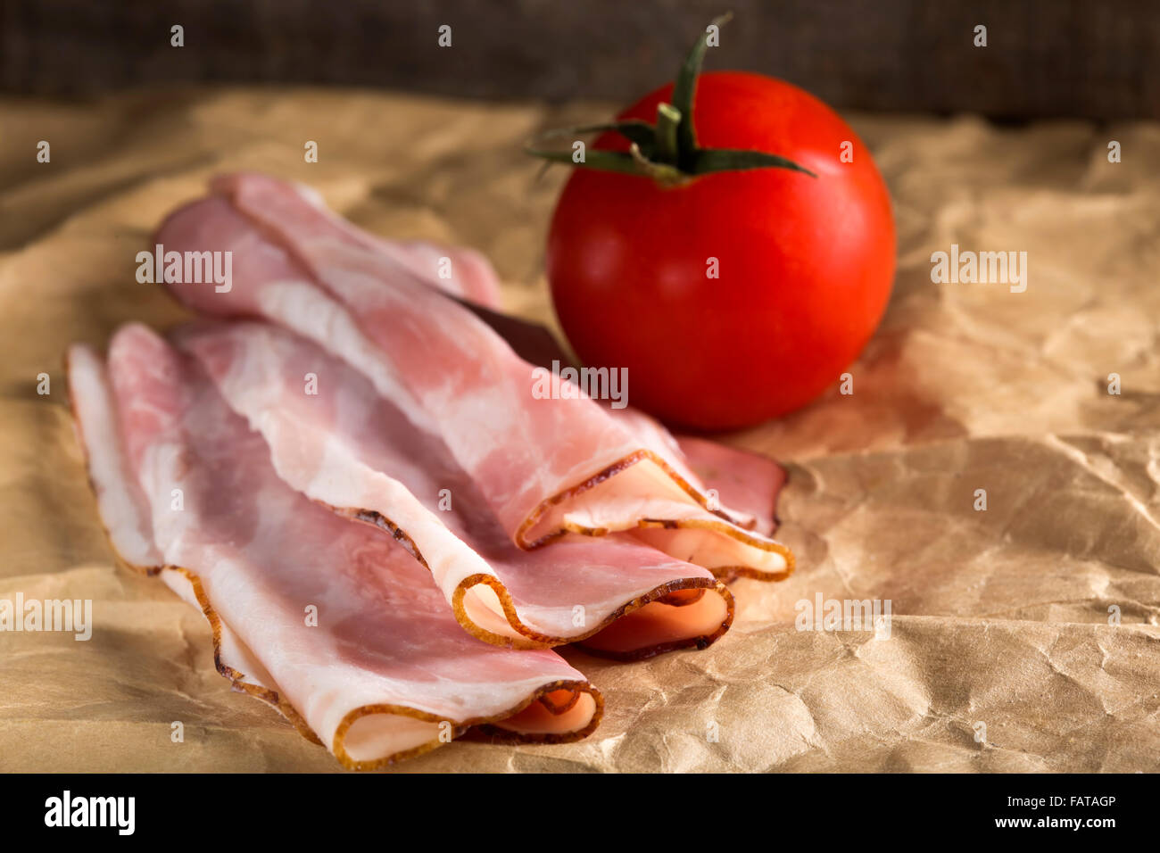 Nahaufnahme von appetitlich Speck auf Papier und eine Kirschtomate Stockfoto