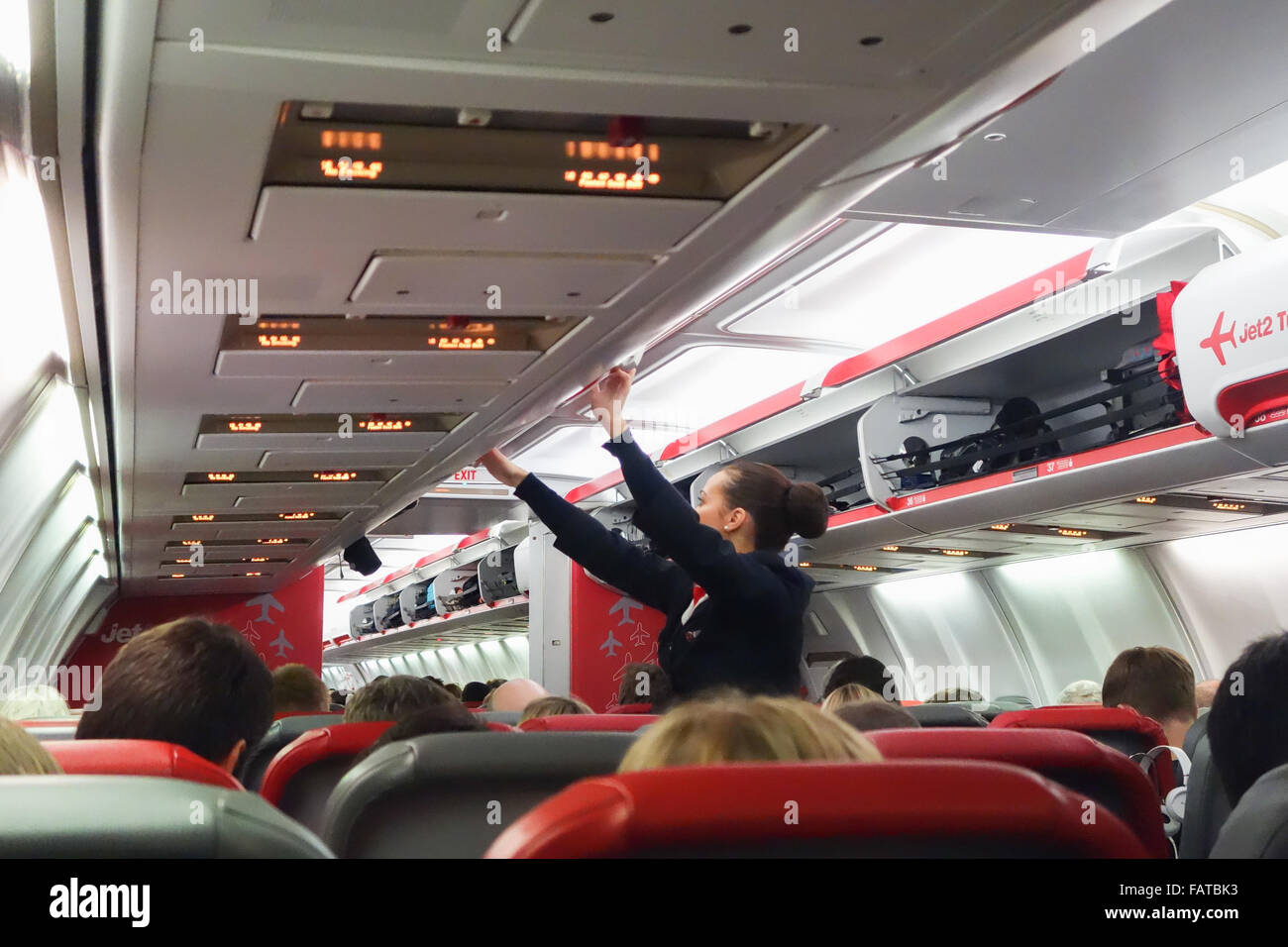 Weiblichen Flugbegleiter überprüfen und schließen Overhead Gepäckschließfächer auf einem Flug Jet2 Stockfoto