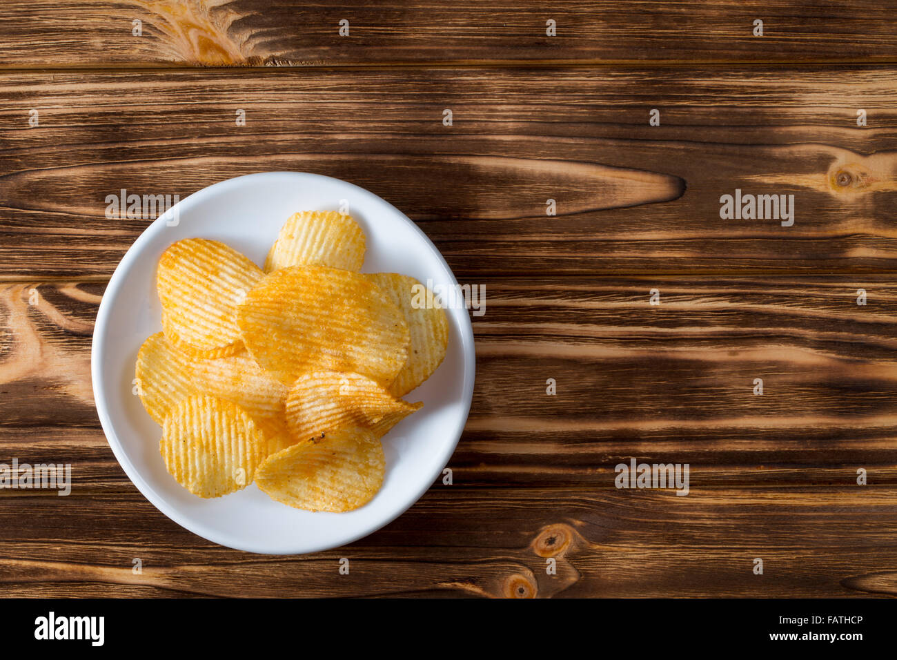 Kartoffel-Chips auf dem hölzernen Hintergrund. Stockfoto