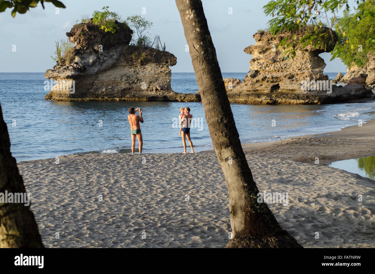 ein Mann fotografiert ein anderes hält ein Kleinkind am Strand in Soufriere St lucia Stockfoto