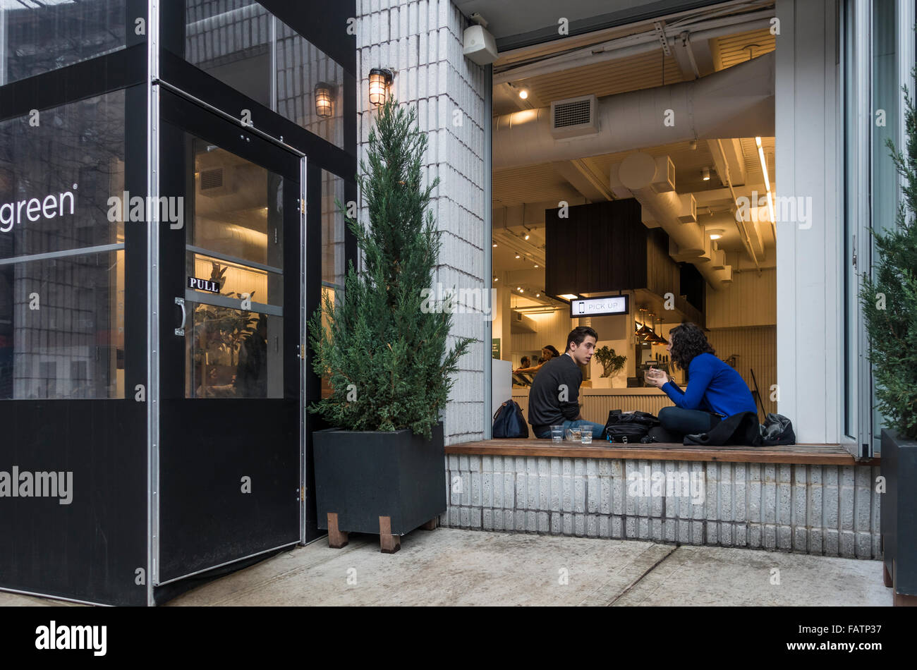 Paar sitzen und Essen in das offene Fenster ein vegetarisches Restaurant in Soho in New York City Stockfoto